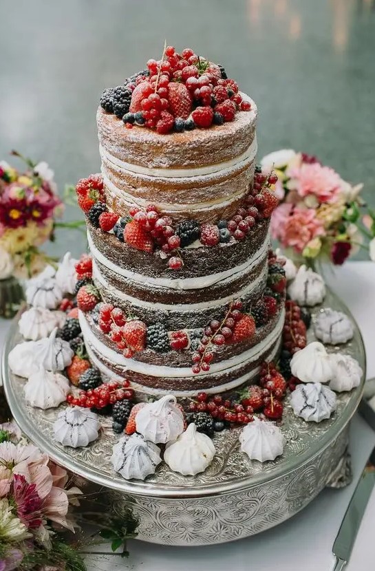 a naked wedding cake with lots of berries and meringues is a lovely idea for a rustic wedding