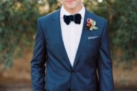 a navy suit, a white shirt, a navy velvet bow tie and a simple boutonniere for a gorgeous look