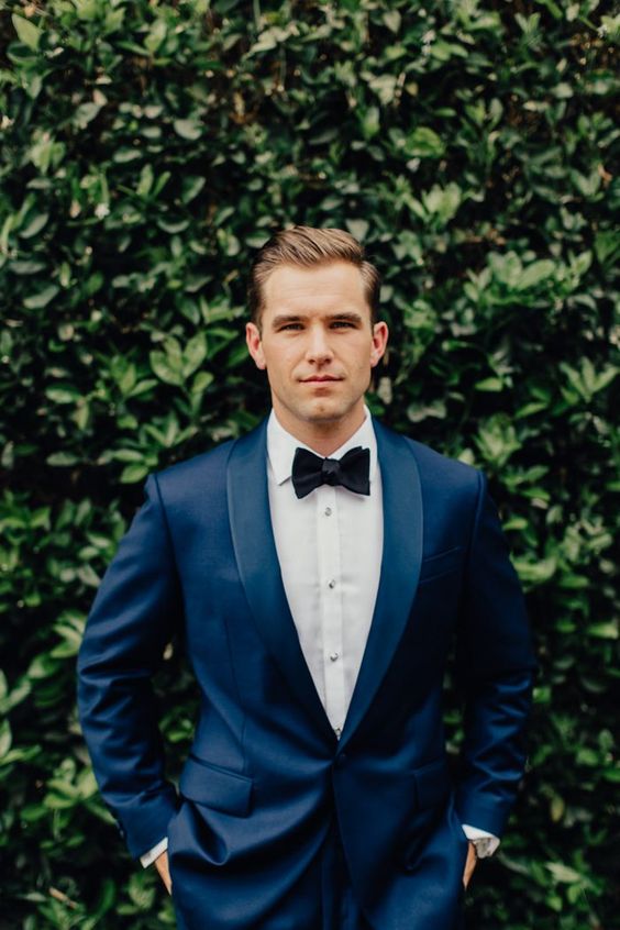 a navy tuxedo with a black bow tie and a white shirt is a chic and bold modern idea