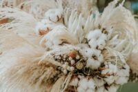 a neutral boho wedding bouquet of cotton, white proteas, berries, pampas grass and spikes