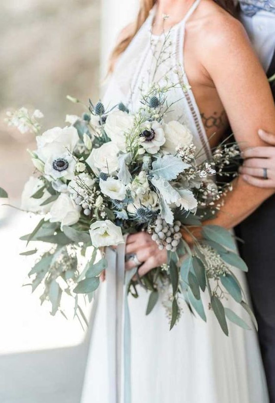 a neutral spring wedding bouquet with white blooms, pale greenery, berries and blooming branches