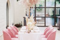 a pink grass overhead centerpiece and matching pink chair make the reception space very romantic