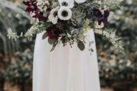 a refined wedding bouquet with dark blooms, white anemones, succulents, greenery and some blooming branches is gorgeous