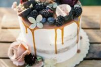 a semi naked fall wedding cake with caramel drizzle, blackberries, figs, blooms and succulents on top