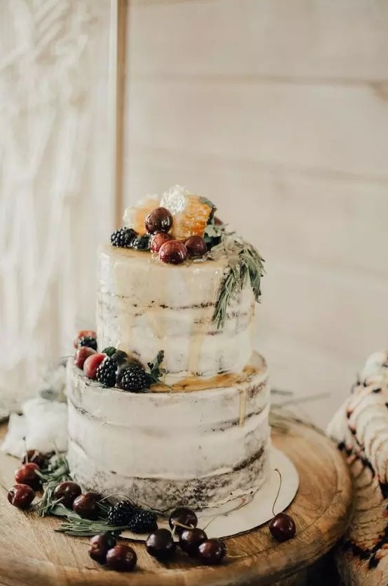 a semi naked wedding cake with caramel drip, fresh berries and fruit and greenery is a gorgeous boho wedding dessert for a vineyard wedding