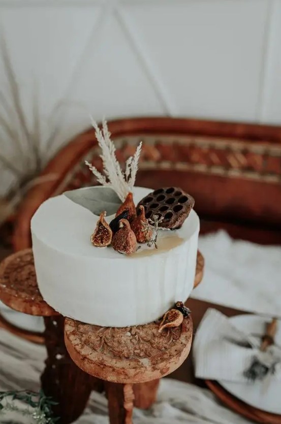 a simple buttercream wedding cake topped with figs, lotus and grasses is a gorgeous idea for a fall wedding