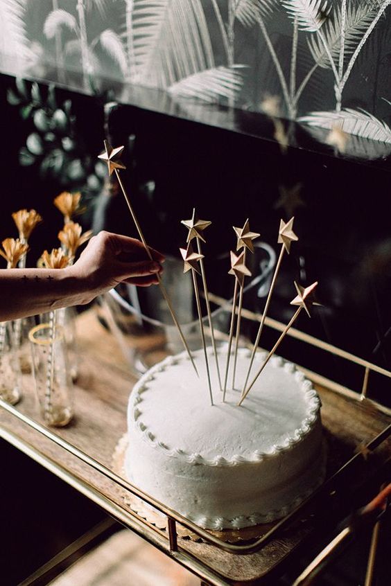 a simple white plain wedding cake with star toppers is a cool glam NYE idea that can be even DIYed
