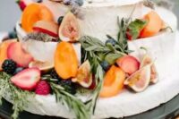 a small and cool cheese wheel wedding cake topped with fresh fruit and berries, herbs for a bright summer wedding
