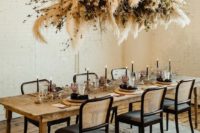 a stylish overhead installation of pampas grass, dried greenery and branches for a Halloween wedding