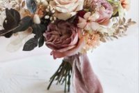 a tender summer wedding bouquet with mauve, ivory and blush blooms and some foliage plus mauve ribbons