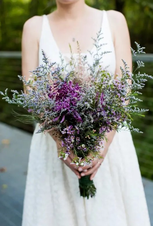 a textural and bold wedding bouquet of purple dahlias, waxflower and lots of simple grasses and wildflowers is amazing for a summer wedding
