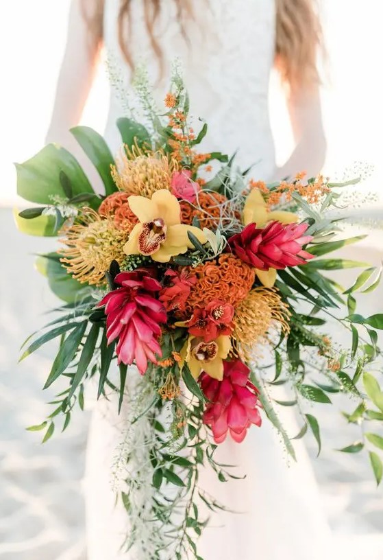 a textural cascading tropical wedding bouquet with fuchsia, yellow, orange blooms and greenery