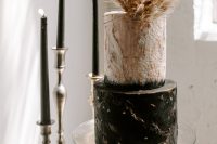 a textural white and black wedding cake with gold leaf and pampas grass and fronds is a very refined option
