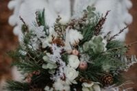 a textural winter wedding bouquet of evergreens, greenery, twigs, berries, pinecones, cotton, feathers and lotus is amazing