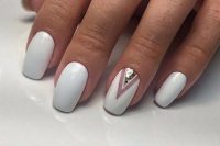 a white manicure with a negative chevron and silver glitter at the base looks amazingly stylish