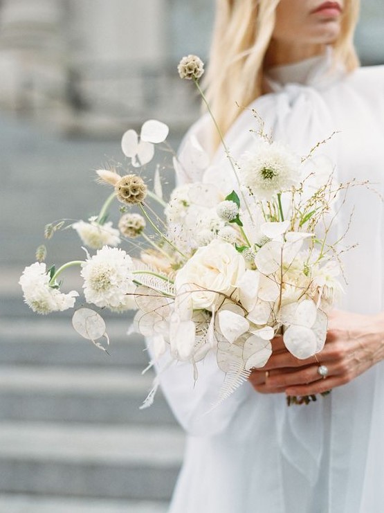 a white wedding bouquet in modern style, with trendy lunaria and some catchy detailing is a fresh idea