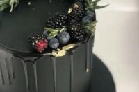 an elegant and moody plain black wedding cake with black drip, gold leaf, blackberries, blueberries and herbs on top is a chic and modern idea to rock