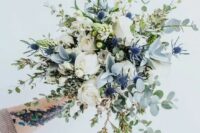 an ethereal bouquet with eucalyptus, blue thistles, white roses and herbs looks very beautiful