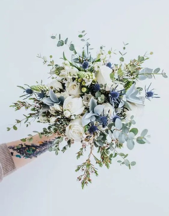 an ethereal bouquet with eucalyptus, blue thistles, white roses and herbs looks very beautiful