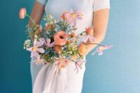 an eye-catchy pastel wedding bouquet with soft orange, lilac and blue blooms looks textural and will fit a spring wedding