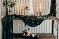 an industrial wedding cake table – a cart with chiken wire, dark green velvet fabric and a lovely naked wedding cake surrounded with candles