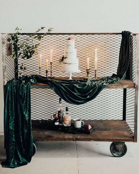an industrial wedding cake table - a cart with chiken wire, dark green velvet fabric and a lovely naked wedding cake surrounded with candles