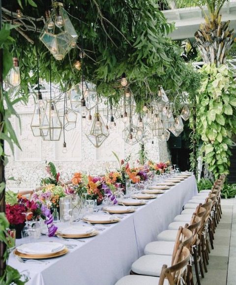 an overhead wedding decoration with lush greenery, bulbs and geometric terrariums