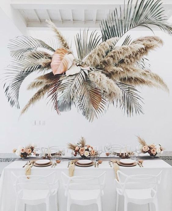 an oversized tropical wedding installation with leaves and pampas grass will make your wedding feel really tropical-like