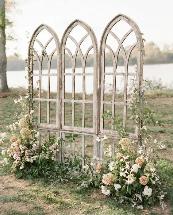 arched elf style doors decorated with greenery and neutral and blush blooms are a beautiful backdrop for a fairy tale wedding