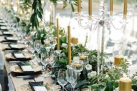 black and gold wedding reception table with lush greenery and gold candles