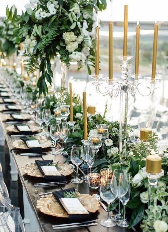 black and gold wedding reception table with lush greenery and gold candles