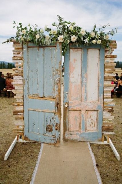 double shabby chic doors decorated with greenery and white blooms are a cool and stylish wedding backdrop