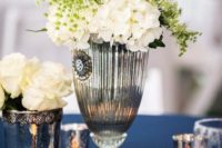 gorgeous wedding table decor – a navy tablecloth, silver mercury glass candles and a vase with white blooms