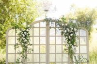 large and beautiful French doors decorated with greenery and white blooms are a sophisticated and chic wedding backdrop