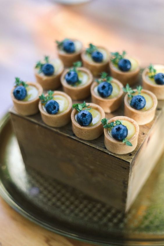 mini tarts with custard and bluberries on top are a very cool and refreshing idea for a wedding