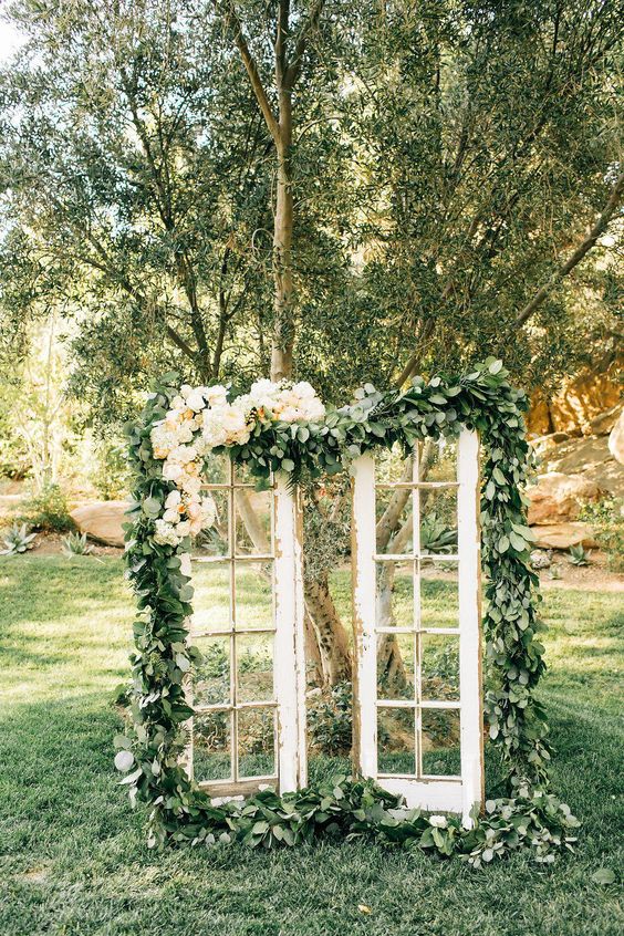shabby chic French doors decorated with greenery and pastel blooms will be a beautiful wedding backdrop for a garden wedding