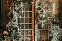 shabby chic arched French doors decorated with greenery and some pastel blooms plus a cowhide rug are a lovely wedding backdrop to rock