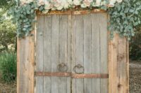 shabby chic rustic doors decorated with greenery, white and blush blooms are amazing for a rustic wedding