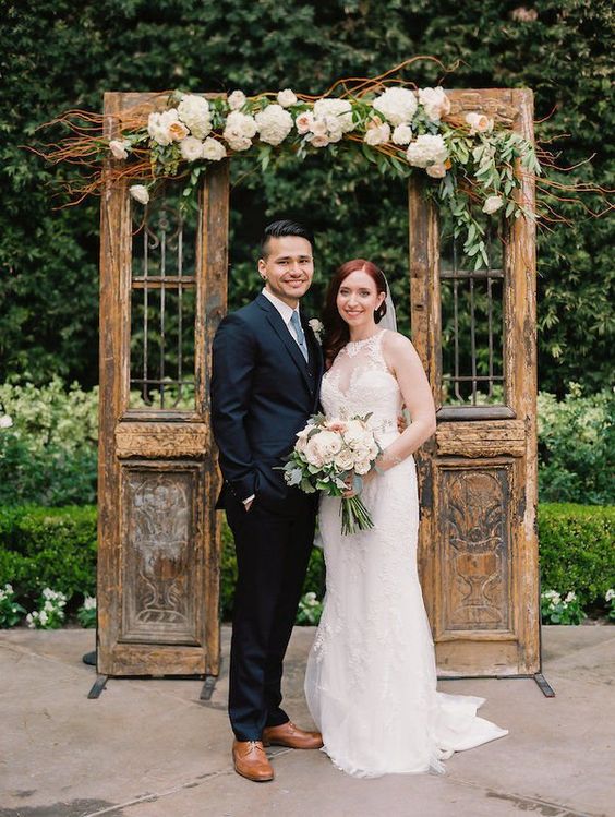 shabby chic stained doors decorated with vines, greenery and pastel blooms are a beautiful and exquisite backdrop for a wedding