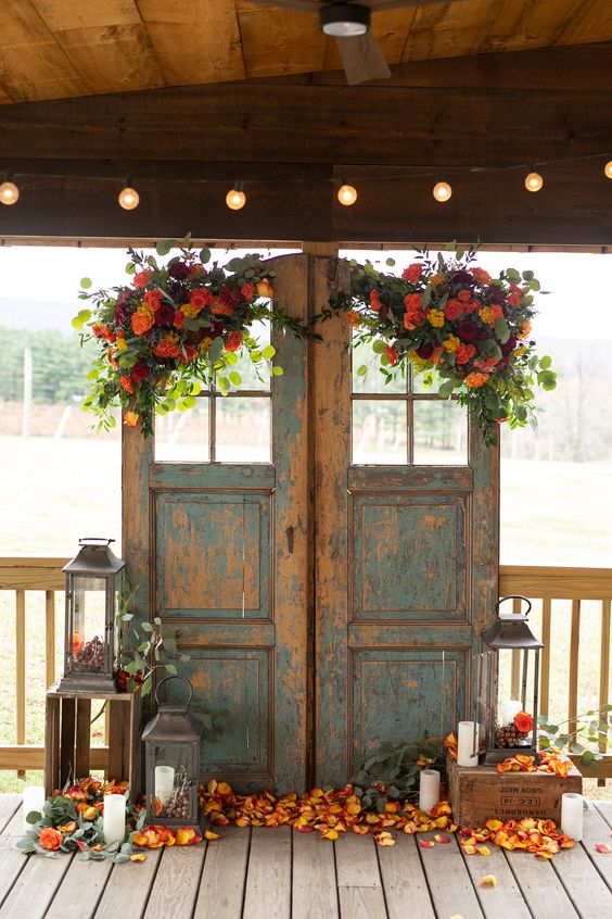 vintage shabby chic double doors with greenery, bold blooms and matching petals on the floor, candle lanterns