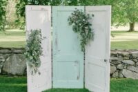 white and a mint doors decorated with greenery are a relaxed and casual wedding backdrop for a wedding with a vintage feel