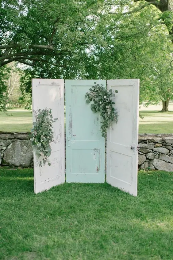 white and a mint doors decorated with greenery are a relaxed and casual wedding backdrop for a wedding with a vintage feel