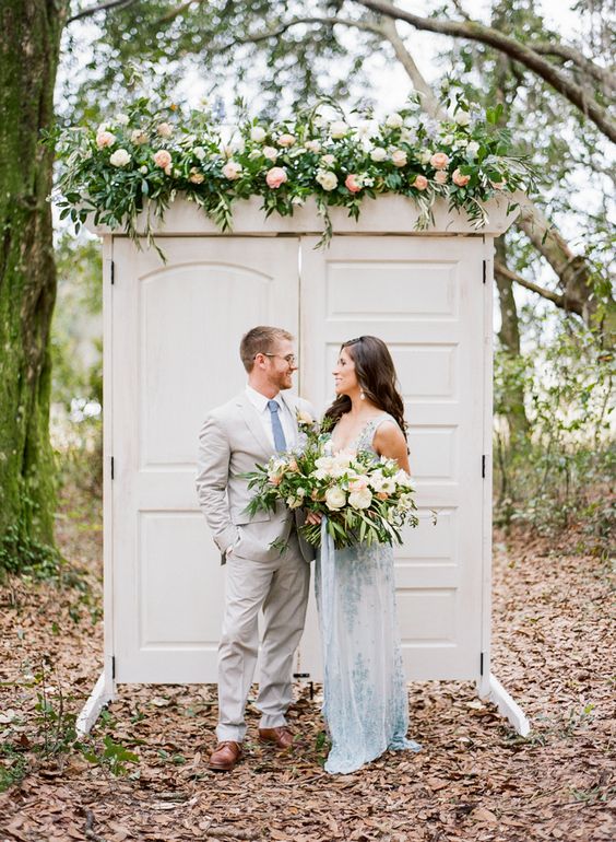 white double doors with greenery and pastel blooms are a lovely wedding backdrop idea for a rustic wedding