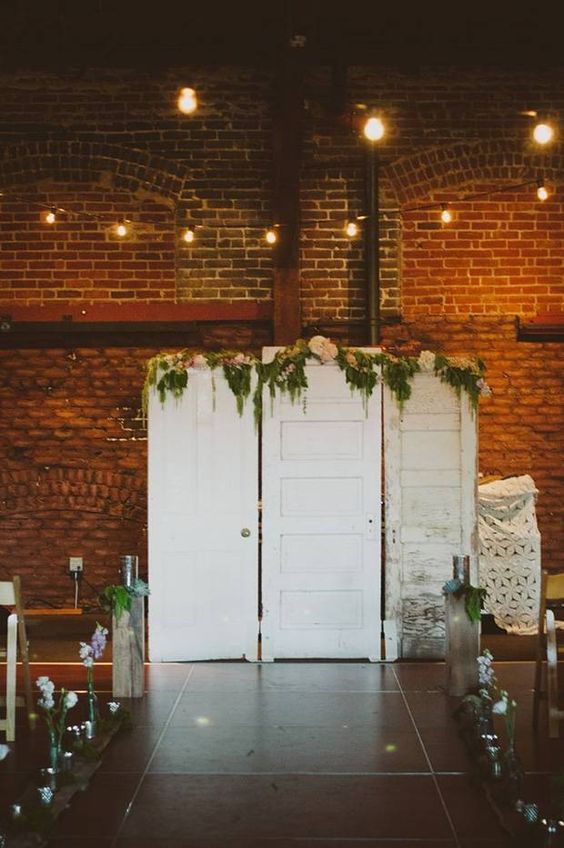 white shabby chic doors decorated with greenery and blush blooms are a lovely and relaxed wedding backdrop to rock