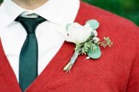 a Christmas groom look with a white shirt, a green tie, a red cardigan and a white floral boutonniere is very bold