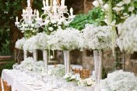a beautiful outdoor wedding reception with baby’s breath arrangements and crystal chandeliers over the table is amazing