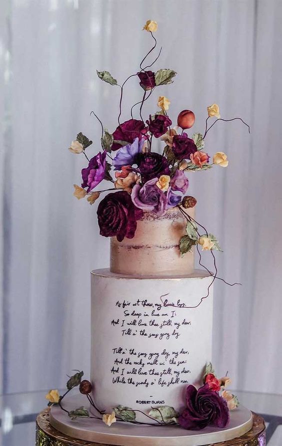 a beige and white wedding cake with quotes, bold blooms and twigs on top is a perfect refined fall wedding dessert