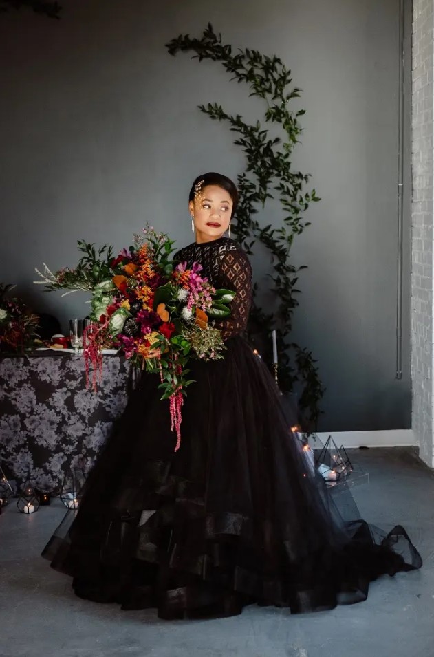 a black wedding ballgown with a crochet lace bodice and long sleeves plus a tiered ruffle skirt and an open back