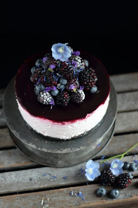 a blackberry and blueberry wedding cheesecake with an oreo base topped with fersh blooms, blackberries and blueberries