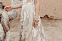 a boho wedding dress with a crochet lace bodice with a halter neckline and a nude skirt with white lace appliques for a boho bride